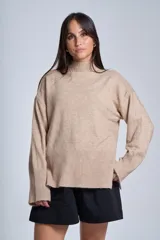 Sweater color beige de tejido de punto, con cuello alto y mangas largas. Presenta detalles acanalados en los puños y el bajo.