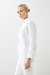 Camisa blanca de corte clásico, con cuello camisero, mangas largas con puños abotonados y cierre frontal con botones.