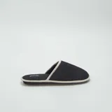 Pantuflas mules negras con borde gris.