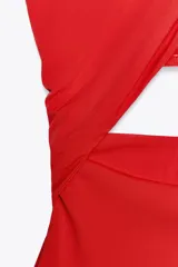 Body rojo de tejido fluido, con cuello halter que se ata al cuello y escote cruzado. Presenta abertura en la espalda y cierre inferior con botones a presión.