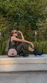 Bandolera pequeña de tela negra, con correa ancha ajustable y cierre superior.