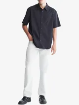 Camisa negra de manga corta confeccionada en algodón. Tiene cuello clásico, cierre frontal con botones, bolsillo de parche en el pecho y corte holgado.