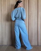 Conjunto de camisa y pantalón de lino blanco. La camisa es de manga larga y se ata en la parte delantera. El pantalón es de corte ancho y tiene cordón en la cintura.