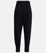 Pantalón zanahoria de crepé negro con pliegues, corte de sastrería, trabillas en la cintura y abertura con botón y cremallera.