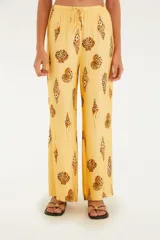 Pantalón de corte ancho color amarillo con estampado de conchas. Tiene cintura alta, corte fluido y cierre discreto.