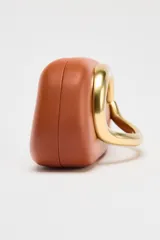 Bolso marrón con forma de caja, con cierre dorado en forma de C y asa de cadena dorada para usar como bandolera.