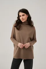 Polera gris holgada de acrílico, con cuello alto y mangas largas.