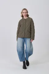 Campera acolchada negra, con diseño capitoné en rombos, cuello redondo y cierre frontal con botones a presión. Posee bolsillos delanteros amplios.