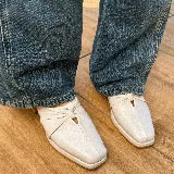 Zuecos negros de cuero con punta cuadrada y detalle de nudo en el empeine.