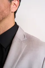 Traje de vestir gris claro, compuesto por saco de dos botones con solapa de muesca, bolsillo de ojal y dos bolsillos de parche. Incluye pantalón de vestir a juego.