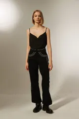 Pantalón negro de corte ancho con tachas plateadas en la cintura y laterales.