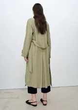 Abrigo largo color beige con cuello de solapa, trabillas en los hombros y cinturón tipo batín.
