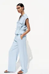 Pantalón celeste de tiro alto con cintura elástica, bolsillos delanteros y pernera ancha.