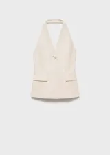 Chaleco largo color crema con cuello halter, espalda abierta, botón joya y bolsillos delanteros.