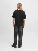 Remera negra de manga corta y cuello redondo, con fit oversize y largo cropped. Presenta un estampado frontal con la palabra "Originals" en blanco y detalles de texto y el número "1990". El cuello y los puños son de color beige.