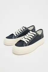 Zapatillas bajas de denim azul oscuro con cordones blancos y suela de plataforma color crema.