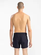 Short de baño color beige con una franja vertical marrón en el lateral. Tiene cintura elástica con cordón ajustable, bolsillos laterales y trasero con cierre, y suspensor de malla fina hipoalergénica.