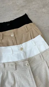 Bermuda color beige de corte ancho, con cintura alta, botón y bolsillos laterales.