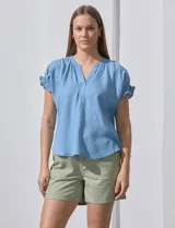 Blusa celeste de lyocell, con cuello a la base y escote en V. Manga corta con detalle de punto smock. Marca Zac & Rachel.