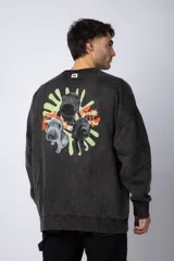 Buzo de cuello redondo y corte oversize en tela friza, color gris con efecto acid wash. Presenta un estampado frontal en color verde lima con un diseño abstracto.