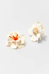 Par de caravanas con forma de flor color crema y centro con cuentas naranjas y negras.