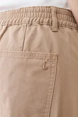 Pantalón de gabardina color tostado, de corte recto, con bolsillos laterales y traseros. Se ajusta a la cintura con cinturón de cuero con estampado animal print.