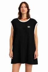 Vestido corto negro de tejido gofrado, sin mangas, con cuello redondo ribeteado en color crema y un pequeño logo ovalado bordado en el pecho.