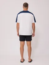 Remera de hombre azul marino con mangas y cuello amarillo, y logo de la marca Rusty estampado en el pecho.