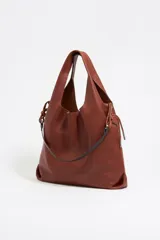 Bolso de mano negro con exterior de piel y estructura blanda. Incluye asa extraíble, bolsillo interior y etiqueta de tejido. Presenta logo metálico BIMBA Y LOLA con acabados metálicos plateados.