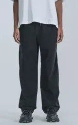 Pantalón negro de corte ancho, con cintura y puños elásticos, bolsillos laterales y rodillas reforzadas. Confeccionado en tejido impermeable y elastizado.