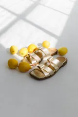 Sandalias negras con tiras anchas cruzadas y detalle de hebillas doradas.