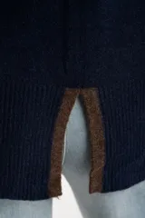 Sweater de punto azul marino con calce oversize. Presenta un detalle de franja vertical color marrón en la parte exterior de ambas mangas y un ribete fino dorado en el escote redondo.