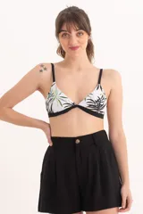 Top de bikini triangular con estampado tropical en tonos verdes y negros sobre fondo blanco. Tiene tirantes finos negros y contorno inferior negro.