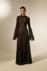 Vestido largo negro de manga larga y cuello alto, confeccionado en poliéster con corte evasé.