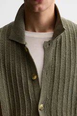 Camisa verde militar de punto con estructura abierta, corte regular fit, cuello solapa, manga corta y cierre frontal con botones.