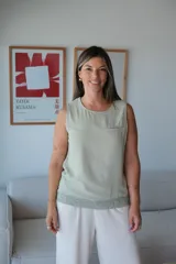 Musculosa sin mangas color verde musgo, con escote redondo y un bolsillo pequeño en el pecho. El ruedo inferior tiene un detalle de tejido de punto en color verde más claro.