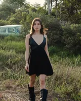 Vestido corto negro, con escote en V profundo en el frente y espalda ajustable. El corpiño parece ser de cuero y la falda de microtul.