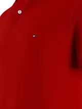 Chomba Tommy Hilfiger color rojo de corte slim, con cuello polo, cartera de dos botones, mangas cortas con ribete blanco y logo de la marca bordado en el pecho.