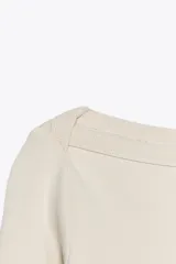 Camiseta negra de algodón con cuello barco y mangas largas.