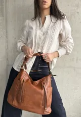 Camisa color beige de lino con detalles de broderie en el frente y mangas largas con puños elásticos.