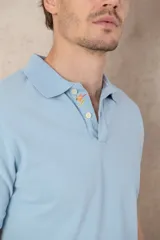 Remera tipo polo color beige, de manga corta y corte clásico. Tiene cuello con botones y está confeccionada en algodón.