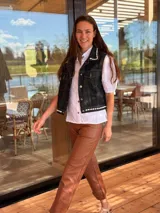 Chaleco de jean negro con apliques de caracoles cosidos a mano en los bordes.