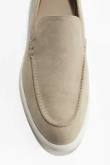 Mocasines color beige de gamuza con costura tradicional y suela blanca de goma.