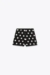 Shorts negros con estampado de lunares blancos, de tiro alto y cierre lateral con cremallera oculta.