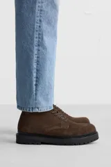 Bota de caña baja color marrón chocolate, de cuero gamuzado, con cordones al tono y suela track color negro.