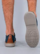 Zapato acordonado azul marino, con capellada combinada en cuero y tejido de red. Suela blanca de goma con vira marrón.