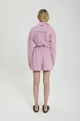 Short ancho de algodón color rosa, con cintura elástica y cordón de ajuste. Presenta un bolsillo lateral con estampado de dos perfiles y la frase "Le monde est à nous".