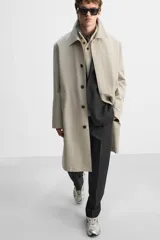 Gabardina color beige de corte relaxed fit, confeccionada en tejido italiano repelente al agua. Tiene cuello solapa, manga larga con puños abotonados, bolsillos de vivo en la cadera, bolsillo interior y abertura en la espalda.