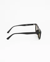 Lentes de sol de montura cuadrada gruesa, color gris ahumado translúcido, con cristales oscuros polarizados. Presentan detalles metálicos en las esquinas superiores del frente.