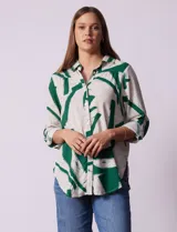 Camisa de manga larga con estampado abstracto en tonos verde y blanco. Cuello con solapa y abertura central con botones. Largo de manga regulable con presilla y botón. Terminación de ruedo anudada opcional.